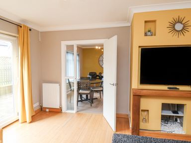 A living room with a wall mounted TV wooden mantel and an open door leading to a dining area at 315 Filey Road Scarborough