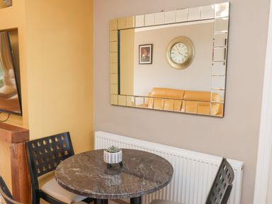 A dining area with a round table and two chairs next to a radiator and a large mirror on the wall at 315 Filey Road in Scarborough