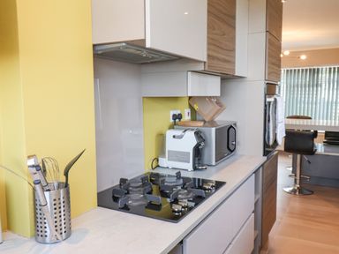A kitchen with a gas stove, microwave, utensils holder, and bar stools at 315 Filey Road Scarborough