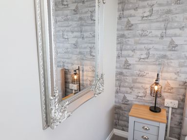 A bedside table with a lamp and animal-themed wallpaper reflected in a wall mirror at 315 Filey Road Scarborough
