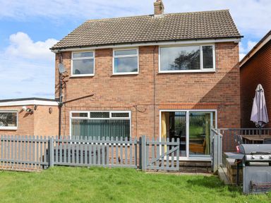 A brick house with upper and lower windows a sliding glass door a fenced patio area lawn garden and outdoor grill at 315 Filey Road Scarborough