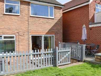 A backyard with a gray wooden fence planter green grass and a brick house with patio furniture at 315 Filey Road Scarborough