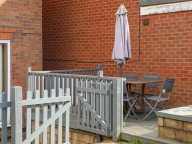 A fenced patio area with a wooden table four chairs and a closed umbrella at 315 Filey Road Scarborough
