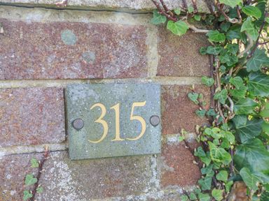A brick wall with a plaque showing the number 315 surrounded by ivy leaves at 315 Filey Road in Scarborough