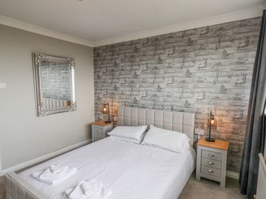 A bedroom with a double bed two bedside tables with lamps and a mirror on the wall at 315 Filey Road in Scarborough