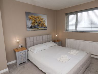 A bedroom with a double bed two bedside tables lamps and a window with blinds at 315 Filey Road Scarborough