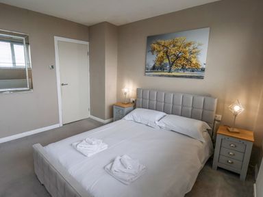 A bedroom with a double bed two bedside tables with lamps a door a mirror and a painting at 315 Filey Road Scarborough