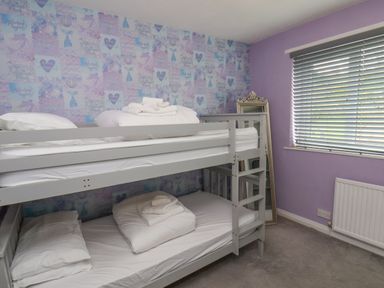 A bedroom with bunk beds white bedding a full length mirror on floor a window with blinds and purple walls at 315 Filey Road Scarborough