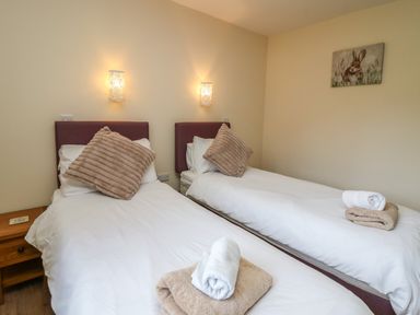 A bedroom with two single beds with pillows and folded towels on each bed at Caban Dulas in Rhayader