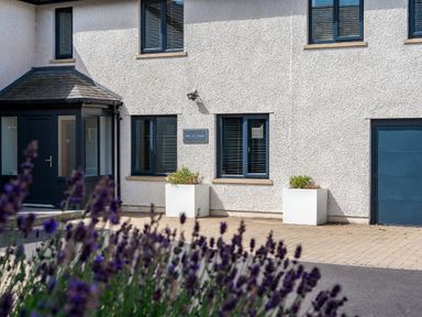 The exterior of a building with windows a door two planters and purple flowers in the foreground at Pen-y-Ghent in Kirkby Lonsdale