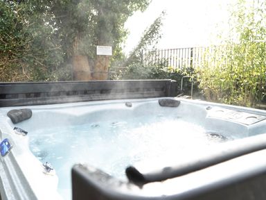 An outdoor hot tub with water bubbling surrounded by plants at Pen-y-Ghent in Kirkby Lonsdale