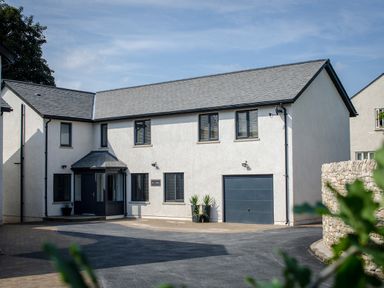 A modern two-story white house with a grey roof and black garage door at Pen-y-Ghent in Kirkby Lonsdale