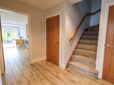 A hallway with wooden floor tiles a staircase with carpet and wooden doors leading to other rooms at Pen-y-Ghent in Kirkby Lonsdale