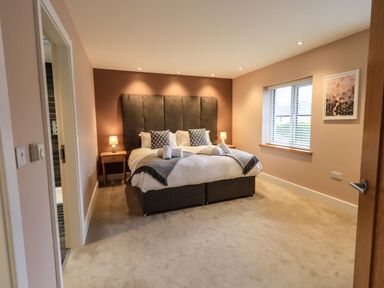 A bedroom with a double bed two bedside tables with lamps a window and a framed picture on the wall at Pen-y-Ghent in Kirkby Lonsdale