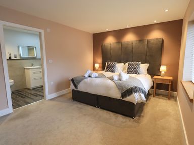 A bedroom with a double bed and bedside tables with lamps and an en suite bathroom at Pen-y-Ghent in Kirkby Lonsdale
