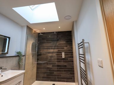 A bathroom with a shower area a sink with a mirror and a towel rack at Pen-y-Ghent in Kirkby Lonsdale
