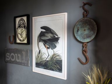 A wall with framed artwork of a bird a horseshoe a sign saying soul and a hanging rusted scale with wheat at Brook Farm in St Nicholas near Halesworth