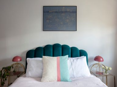 A bedroom with a teal headboard a bed with white pillows and a multicolored cushion two red lamps on golden side tables and a framed artwork on the wall at Brook Farm in St Nicholas near Halesworth