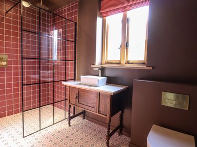 A bathroom with a walk-in shower with red tiles a wooden vanity with a white sink a window above the sink and a toilet with a built-in flush panel at Brook Farm in St Nicholas near Halesworth