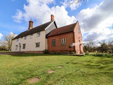 A two section house with brick and plaster walls surrounded by grass and trees at Brook Farm in St Nicholas near Halesworth