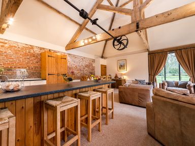 A living room with wooden beams exposed brick wall wooden furniture and leather sofas at Mallard in Wheatacre