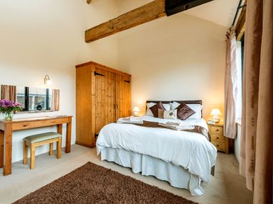 A bedroom with a bed pillows bedside tables wooden wardrobe desk and window at Mallard in Wheatacre