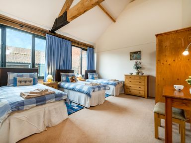 A bedroom with three single beds a wooden dresser a wooden wardrobe and a wooden desk with a chair at Mallard in Wheatacre