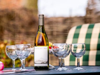 A table with a bottle of Cloudy Bay Sauvignon Blanc and four empty glasses outdoors at Mallard in Wheatacre