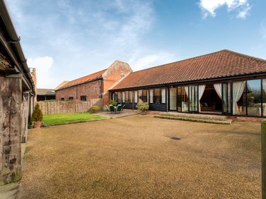 An outdoor courtyard with patio furniture and glass windows of a building with tiled roof at Mallard in Wheatacre