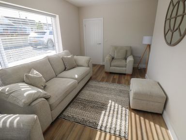 A living room with a sofa armchair ottoman rug and floor lamp at Wychwood in Hook near Haverfordwest