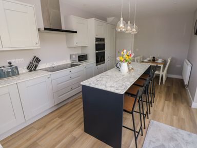 A kitchen with an island and chairs and a dining area at Wychwood in Hook near Haverfordwest