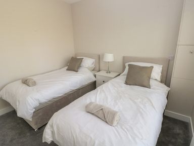 A bedroom with two single beds bedside table with lamp and rolled towels at Wychwood in Hook near Haverfordwest
