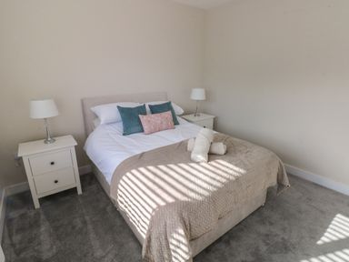 A bedroom with a bed with pillows and towels and two nightstands with lamps at Wychwood in Hook near Haverfordwest