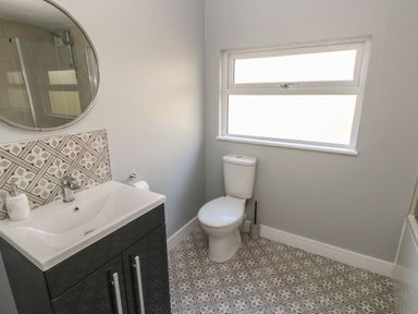 A bathroom with a sink cabinet mirror toilet and tiled floor at Wychwood in Hook near Haverfordwest