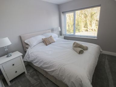 A bedroom with a double bed white bedding rolled towels bedside tables and lamps at Wychwood in Hook near Haverfordwest