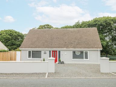 A single story house with a red front door and gravel driveway at Wychwood in Hook near Haverfordwest