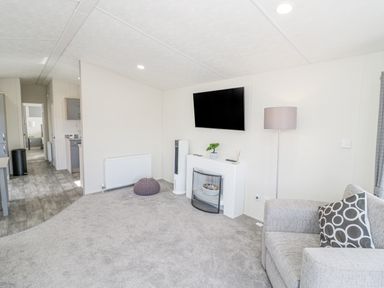 A living room with a sofa and a television mounted on the wall at Long Acres Lodge in Evesham