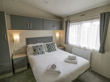 A bedroom with a double bed pillows bedside tables and cabinets at Long Acres Lodge in Evesham