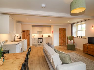 An open plan living room and kitchen with wooden doors and flooring at 8 Rookhaye in Salisbury