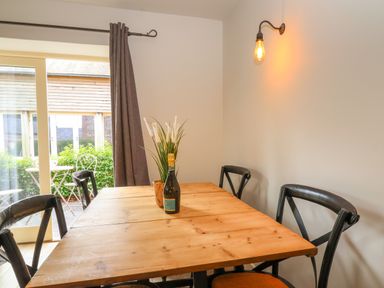 A wooden dining table with four black chairs a bottle and a plant on the table and a wall light at 8 Rookhaye in Salisbury