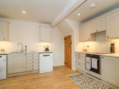A kitchen with white cabinets a wooden door and appliances including a dishwasher and oven at 8 Rookhaye in Salisbury