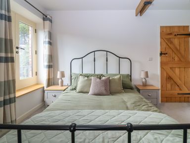 A bedroom with a bed with green bedding and pillows beside two bedside tables with lamps at 8 Rookhaye in Salisbury