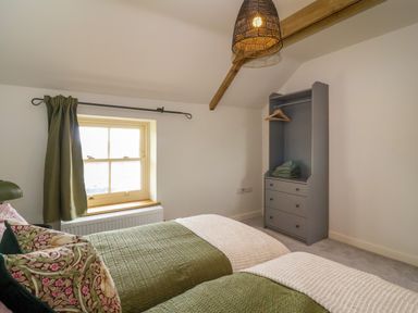 A bedroom with two beds green bedding a window with green curtains a grey wardrobe and a ceiling light at 8 Rookhaye Salisbury