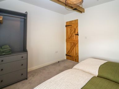 A bedroom with two single beds a wooden door and a gray wardrobe at 8 Rookhaye in Salisbury