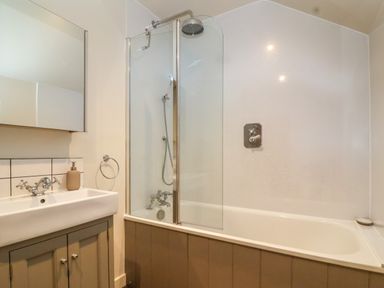 A bathroom with a bathtub shower combination and a sink with mirror at 8 Rookhaye in Salisbury