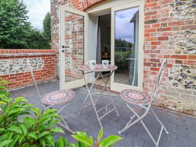 A small outdoor patio area with two chairs and a table with two mugs outside open glass doors at 8 Rookhaye in Salisbury