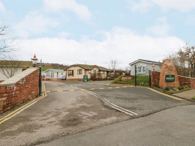Gated entrance to a residential area with houses and a driveway at Plot 32 High Hesket near Armathwaite