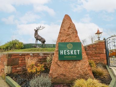 A stone monument with a Hesket Caravan Park sign and a sculpture of a stag behind it at Plot 32 High Hesket near Armathwaite