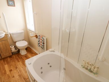 A bathroom with a toilet sink bathtub and wooden floor at Plot 32 High Hesket near Armathwaite
