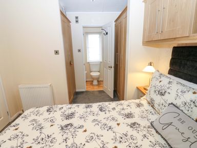 A bedroom with a bed and access to a bathroom at Plot 32 High Hesket near Armathwaite